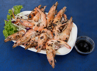Shrimp cooked on a grill. Sauce, salad