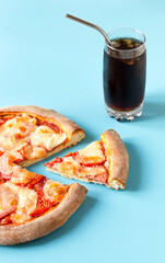 pizza and slice of pizza on a blue background and soda with ice and a metal straw. fast food and copy space