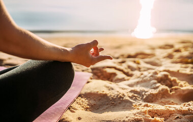 Close up yoga background. The girl sits on the beach by the sea in the lotus position. Side view. No face, hands, feet, sand. Meditation, balance, life balance, pacification, relaxation