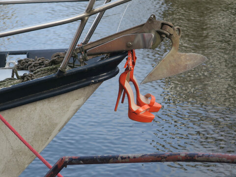 orange high heels hanging under an anchor on the prow of a boat
