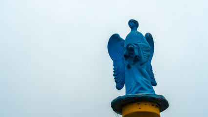 Low angle view of a transparent statue of blue angel. Religion or LGBTQ symbol. Transgender concept.