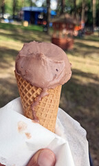 Melting chocolate ice cream cone due to heat or hot weather in summer against trees