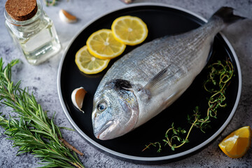 Raw fresh dorada fish with lemon slices and greens