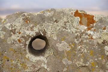 Lichen-encrusted rock with hole bored in it, Karahunj (Carahunge) Observatory near the town of Sisian, Armenia