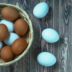 several fresh chicken eggs in a straw basket on a wooden background. Healthy eating concept