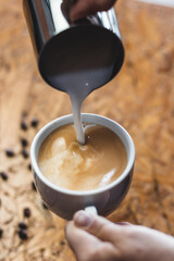 pouring milk into a cup of cappuccino