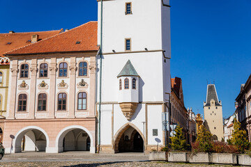 Main town Peace square, gothic white city hall tower, Mikulov Gate, Medieval narrow street, renaissance and baroque historical buildings, arcade, sunny day, Kadan, Czech Republic