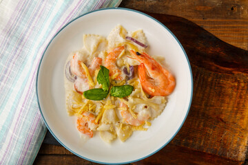 Pasta with shrimps in a creamy sauce on a gray plate on a wooden table on a napkin.