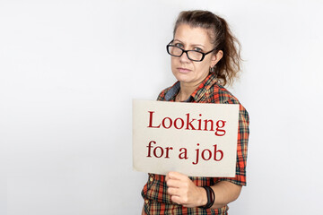 A middle-aged woman with a sad serious face and a sign in her hands with the inscription - Looking for a job, a woman lost her job because in the country quarantine, lockdown due to a pandemic