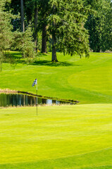 Obraz premium Golf course with gorgeous green and pond.
