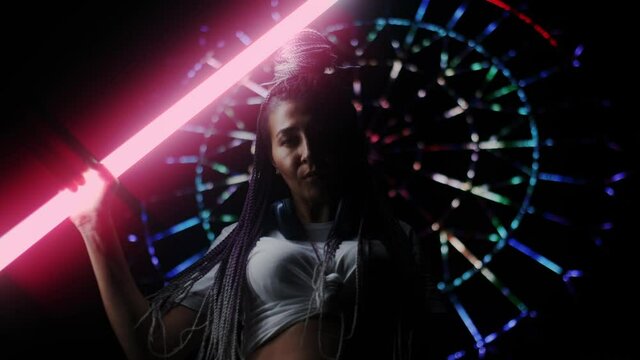 Proud Serious Female Model Posing with Shiny Fluorescent Tube lamp. Extraordinary Stylish Look of Sexy Girl Holding Astera Tube. Nightlife and High Fashion Concept