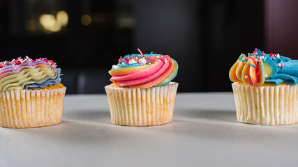 Matte cupcakes in yellow, blue and pink on a light surface. Selective focus. Birthday or Christmas cake, holiday.