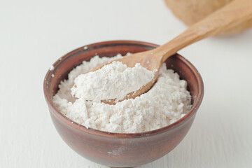 Fototapeta na wymiar Coconut flour in a wooden spoon. Healthy foods.
