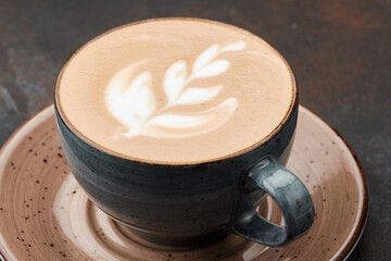 Latte art coffee on grey table. Cup of cappuccino with froth with latte art on grey background. Beautiful dishes.