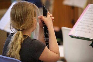 Close-up of a girl with long blonde hair in a dark T-shirt a young musician in a class at school...