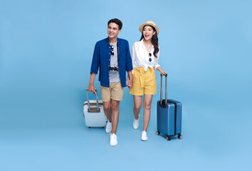 Happy Asian couple tourist with luggage enjoying their summer vacation getaway together isolated on blue background.