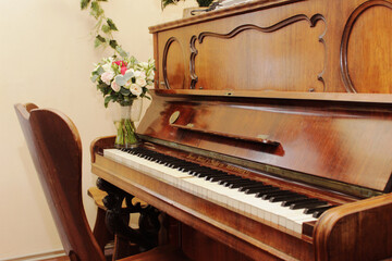 Fototapeta na wymiar Old brown piano with fresh flowers