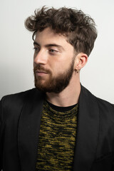 Fototapeta premium Portrait of a bearded young guy on a white wall moth a new haircut.