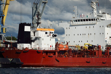 Cargo ships loading in port terminal. Cranes in the background. Baltic sea. Bunkering, fuel and...