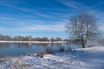 beautiful frozen river called werdersee at sunny warm white winter day with snowy dike and cloudy sky in bremen