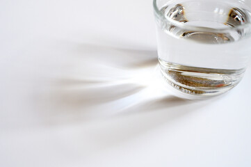 a glass cup of clear water on white background and reflection from the light. space for text