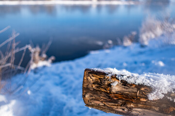 closeup of fallen trunk covered with snow with beautiful frozen river called werdersee in the background in bremen