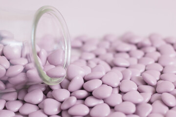 Heart candy in glass jar on purple background. Valentines day concept. Background. Monochrome