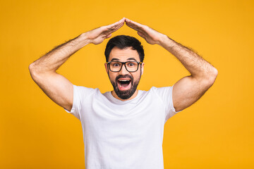 Happy satisfied handsome young man standing with roof gesture hands on head and looking with toothy...