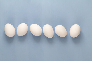 group of white chicken eggs on light blue background with stainless steel whisk , empty space for text
