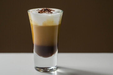 Coffee drink shot with a nutty note with fluffy milk foam, decorated with chocolate shavings