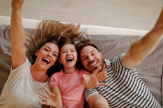 Top view of happy family is having fun in bedroom. Enjoying being together. - Powered by Adobe