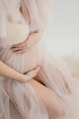 pregnant woman in a lush light dress stroking her belly with her hands