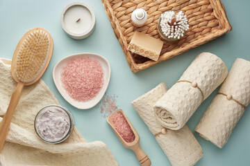 Pink bath salt, scrub, handmade soap, bamboo cotton swabs, muslin towels and other body care supplies. View from above.