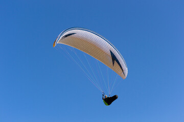 A paraglide flying gliding on a clear blue sky at the golden hour with a nice wind windy breeze on a sunny day 