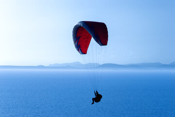 A paraglide flying gliding on a clear blue sky at the golden hour with a nice wind windy breeze on a sunny day 