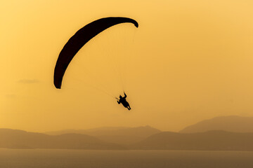 A paraglide flying gliding on a clear blue sky at the golden hour with a nice wind windy breeze on a sunny day 