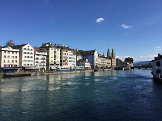 The Limmat River and the Limmatquai waterfront promenade in Zürich, Switzerland. The Grossmünster protestant church's towers can be seen in the background.