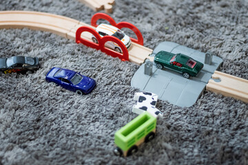 Tiny metal toy cars on a wooden railway on a playground on a grey carpet