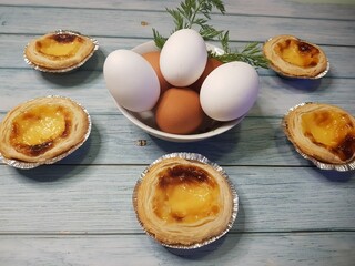 Composition of belem cakes and decoration with bowl of eggs on aged wood