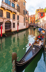 Fototapeta na wymiar Moored gondola on a narrow canal in Venice, Italy, Europe