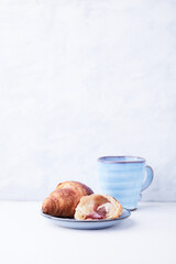 Croissant with coffee on bright wooden background. Copy space.