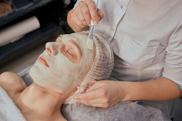 Professional facial skin care. Applying clay to the face with a brush. Beauty salon.