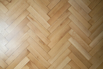 Classic old wooden parquet laying in the form of a herringbone in light brown color. Imeless classics in the design of the floor in the house.