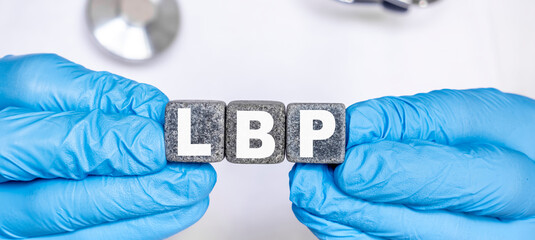 LBP Low back pain - word from stone blocks with letters holding by a doctor's hands in medical protective gloves