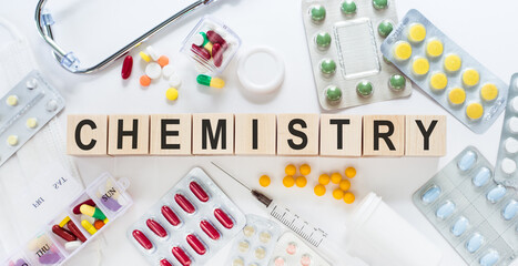 CHEMISTRY medicine word on wooden blocks on a desk. Medical concept with pills, vitamins, stethoscope and syringe on the background.