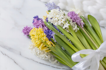 Fototapeta premium Bouquet of spring colored flowers of hyacinths. White marble background and fluffy knitted plaid