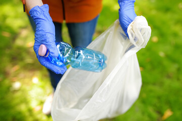 Volunteer picking up the plastic garbage and putting it in biodegradable trash-bag on outdoors....