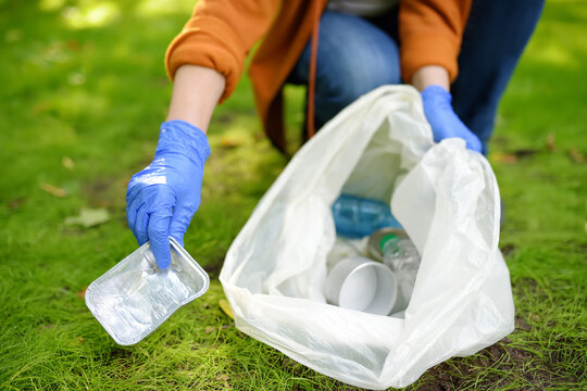 Volunteer picking up the plastic garbage and putting it in biodegradable trash-bag on outdoors. Ecology, recycling and protection of nature. Environmental protection.