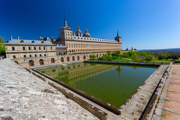 Fototapeta na wymiar El Escorial, Spain- March 17, 2021: Monastery of El Escorial. Facade with parade ground and gardens of the Escorial Monastery. Spanish Royal Palace. National Heritage. Culture of the Spanish royalty.