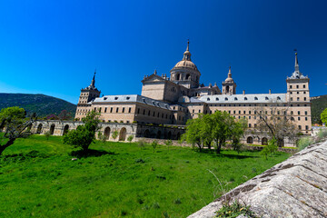 Fototapeta na wymiar El Escorial, Spain- March 17, 2021: Monastery of El Escorial. Facade with parade ground and gardens of the Escorial Monastery. Spanish Royal Palace. National Heritage. Culture of the Spanish royalty.